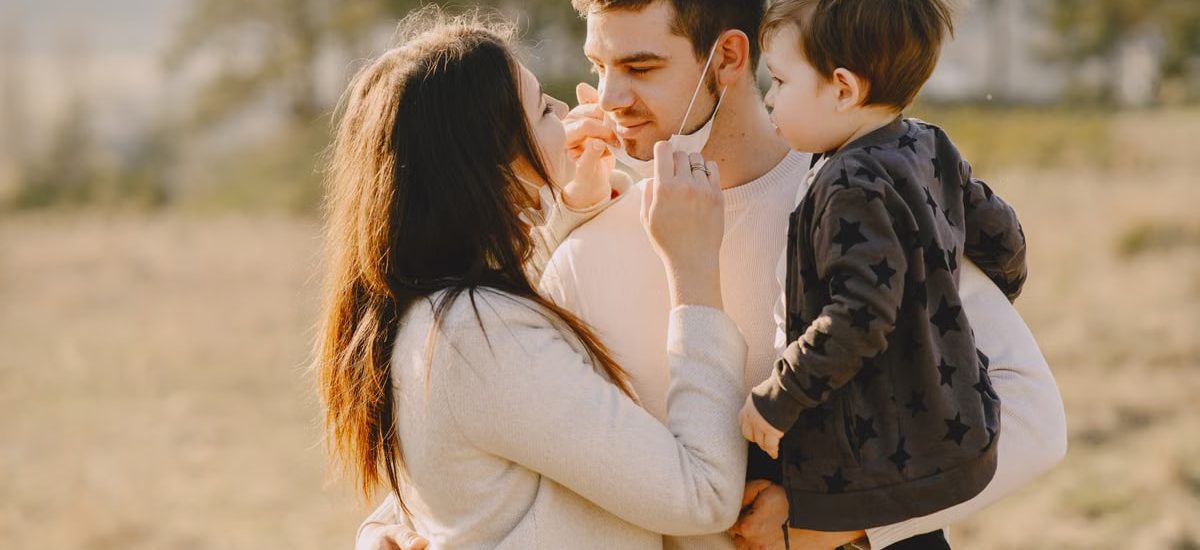 Family sharing affectionate moments outdoors with parents and child enjoying the sunny day.