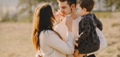 Family sharing affectionate moments outdoors with parents and child enjoying the sunny day.