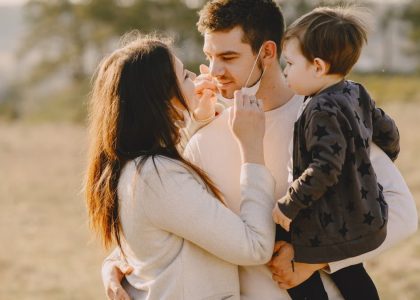 Family sharing affectionate moments outdoors with parents and child enjoying the sunny day.