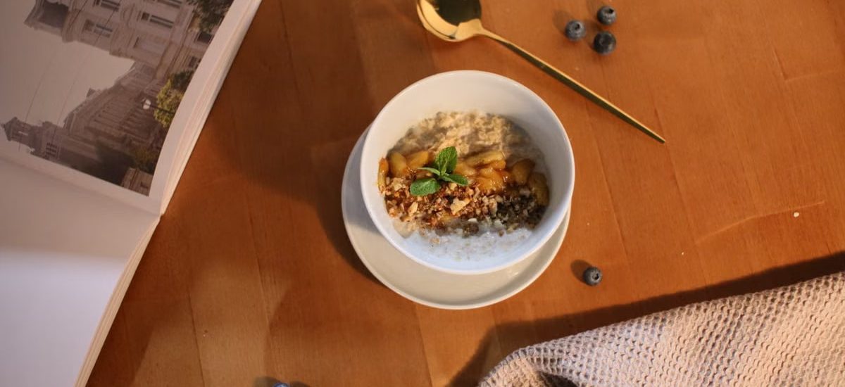 A delicious oatmeal bowl topped with nuts and mint on a wooden table.